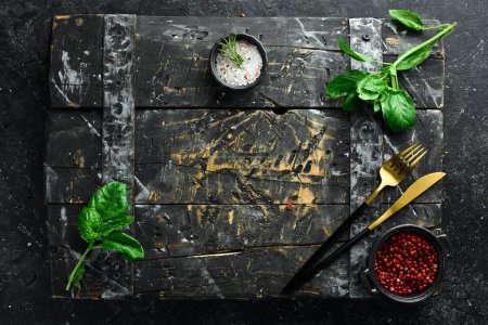 Photo for Cooking background: cutlery, spices and basil. On a black stone background. - Royalty Free Image