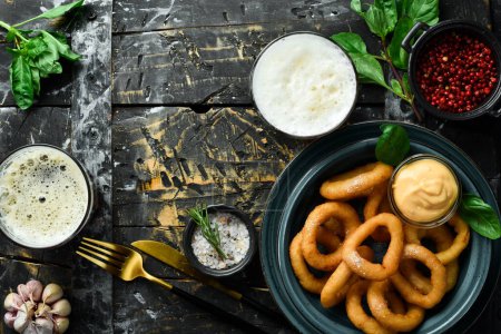 Photo for Appetizer. Fried onion rings with sauce and salt. On a black stone background. - Royalty Free Image