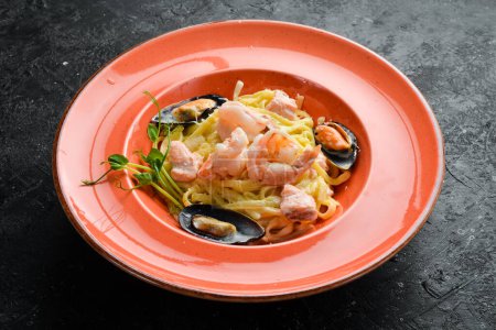 Photo for Seafood. Pasta with shrimp, mussels, cheese and basil in a plate. Italian dish. On a black stone background. - Royalty Free Image