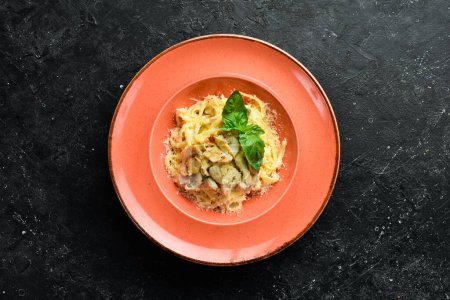 Photo for Pasta with chicken fillet, mushrooms, cheese and basil in a plate. Italian dish. On a black stone background. - Royalty Free Image