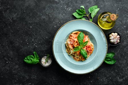 Photo for Pasta with chicken fillet, tomatoes and basil in a plate. Italian dish. On a black stone background. - Royalty Free Image