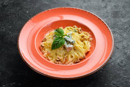 Foto de Pasta de espaguetis con queso y albahaca en un plato. Sobre un fondo de piedra negra. - Imagen libre de derechos