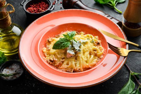 Téléchargez les photos : Pâtes spaghetti au fromage et basilic dans une assiette. Sur un fond de pierre noire. - en image libre de droit