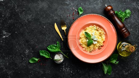 Téléchargez les photos : Pâtes spaghetti au fromage et basilic dans une assiette. Sur un fond de pierre noire. - en image libre de droit