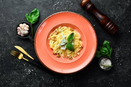 Foto de Pasta de espaguetis con queso y albahaca en un plato. Sobre un fondo de piedra negra. - Imagen libre de derechos