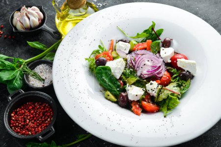 Téléchargez les photos : Salade grecque traditionnelle aux légumes. Sur un fond de pierre noire. - en image libre de droit