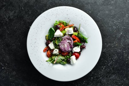 Téléchargez les photos : Salade grecque traditionnelle aux légumes. Sur un fond de pierre noire. - en image libre de droit
