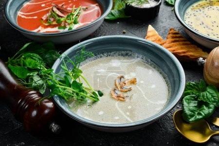 Photo for Mushroom cream soup with cream and conjut. In a blue plate. On a black stone background. - Royalty Free Image