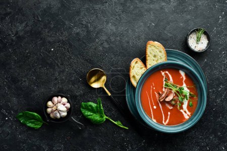 Photo for Tomato soup with bacon, onion and cream. Mexican cuisine. On a black stone background. - Royalty Free Image