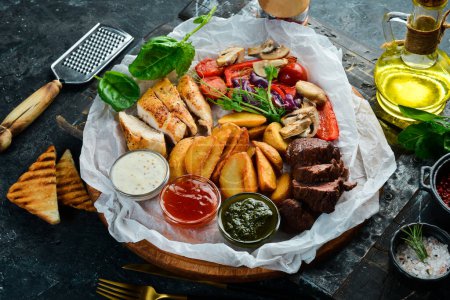 Téléchargez les photos : Barbecue. Steak de veau grillé et poitrine de poulet avec légumes grillés sur une planche en bois. Sur un fond de pierre noire. - en image libre de droit