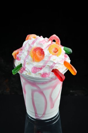 Téléchargez les photos : Milkshake aux fraises dans une tasse en plastique. sur fond noir. Espace libre pour le texte. - en image libre de droit