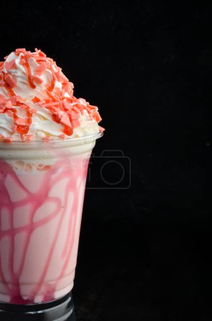 Photo for Strawberry milkshake in a plastic cup. on a black background. Free space for text. - Royalty Free Image