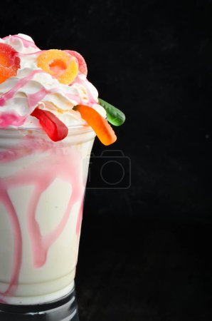 Téléchargez les photos : Milkshake aux fraises dans une tasse en plastique. sur fond noir. Espace libre pour le texte. - en image libre de droit