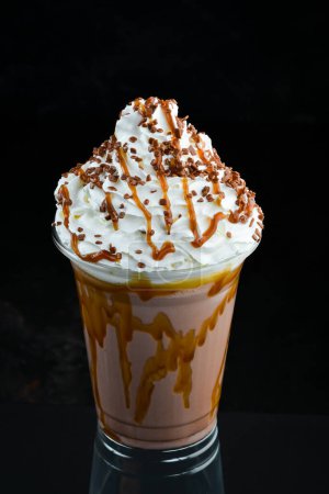 Téléchargez les photos : Milkshake au caramel dans une tasse en plastique. sur fond noir. Espace libre pour le texte. - en image libre de droit