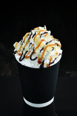 Photo for Caramel milkshake in a plastic cup. on a black background. Free space for text. - Royalty Free Image