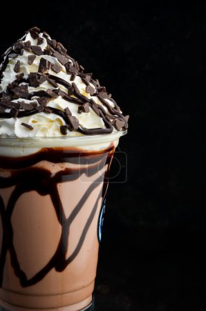 Téléchargez les photos : Milkshake au chocolat dans une tasse en plastique. sur fond noir. Espace libre pour le texte. - en image libre de droit