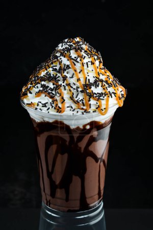 Téléchargez les photos : Milkshake au chocolat dans une tasse en plastique. sur fond noir. Espace libre pour le texte. - en image libre de droit