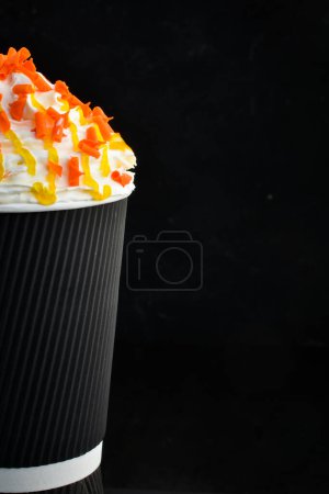 Téléchargez les photos : Café aux fruits confits et crème dans une tasse en papier. sur fond noir. Espace libre pour le texte. - en image libre de droit