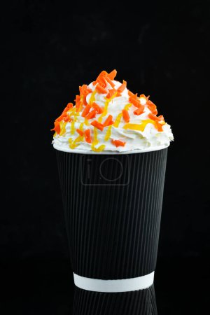 Photo for Coffee with candied fruit and cream in a paper cup. on a black background. Free space for text. - Royalty Free Image