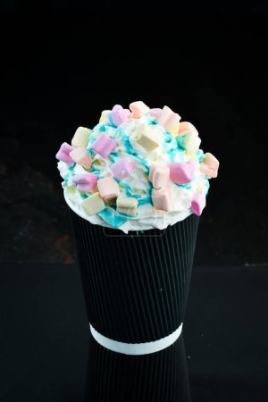 Photo for Coffee with marshmallows and cream in a paper cup. on a black background. Free space for text. - Royalty Free Image