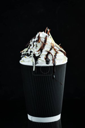 Téléchargez les photos : Café au chocolat et crème dans une tasse en papier. sur fond noir. Espace libre pour le texte. - en image libre de droit