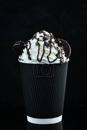 Téléchargez les photos : Café au chocolat et crème dans une tasse en papier. sur fond noir. Espace libre pour le texte. - en image libre de droit