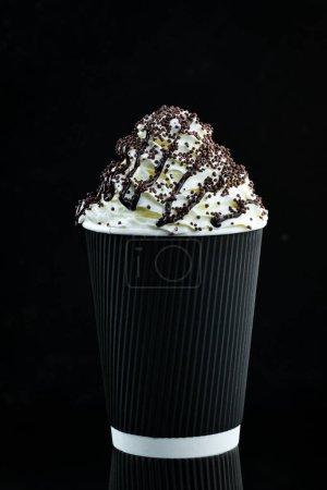 Foto de Café con chocolate y crema en una taza de papel. sobre un fondo negro. Espacio libre para texto. - Imagen libre de derechos