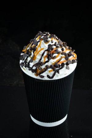 Téléchargez les photos : Café au caramel et crème dans une tasse en papier. sur fond noir. Espace libre pour le texte. - en image libre de droit
