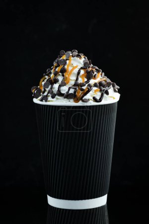 Téléchargez les photos : Café au caramel et crème dans une tasse en papier. sur fond noir. Espace libre pour le texte. - en image libre de droit