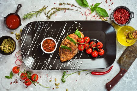 Photo for Baked chicken fillet with basil and salsa sauce on a black plate. Top view. Free space for text. - Royalty Free Image