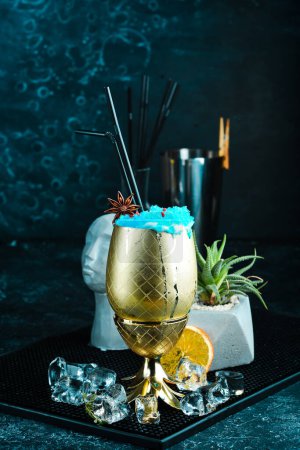 Foto de Cóctel Blue Lagoon en una copa de metal. Sobre un fondo negro. Menú bar. - Imagen libre de derechos