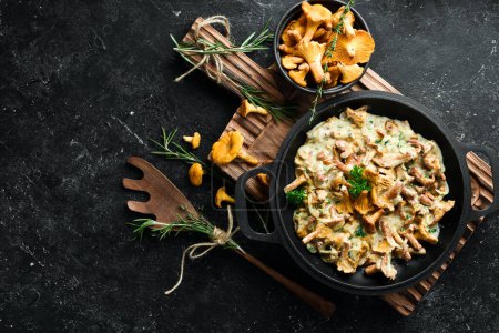 Photo for Cooked chanterelle mushrooms in a cream sauce, in a pan on the kitchen table. Top view. Free space for text. - Royalty Free Image