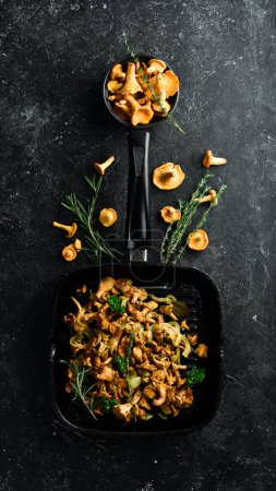 Photo for Cooked chanterelle mushrooms with onions and spices in a pan on the kitchen table. Top view. Free space for text. - Royalty Free Image