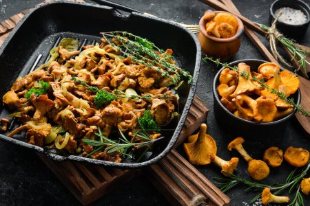 Photo for Chanterelle mushrooms fried with onions and spices in a pan on the kitchen table. Top view. Free space for text. - Royalty Free Image