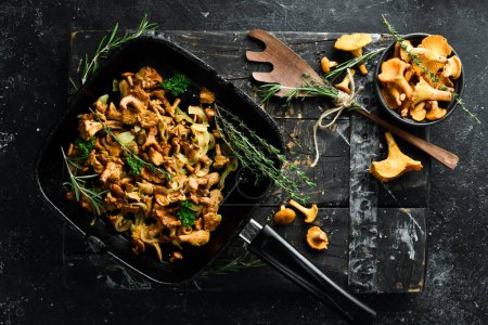 Téléchargez les photos : Champignons Chanterelle frits avec des oignons et des épices dans une casserole sur la table de cuisine. Vue de dessus. Espace libre pour le texte. - en image libre de droit