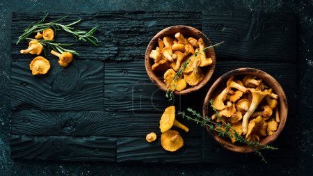 Photo for Organic wild chanterelle mushrooms in a bowl. On a black stone background. Top view. - Royalty Free Image