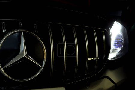 Foto de Rejilla de cromo Mercedes Benz con estrella Benz y logotipo amg con faro led de clase c negra modelo AMG c200 coupé en el garaje oscuro durante el servicio de control de mantenimiento - Imagen libre de derechos