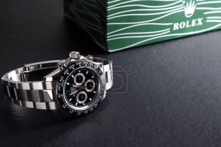Photo for Rolex wristwatch model cosmograph daytona oyster perpetual superlative chronometer with black ceramic bezel stainless steel body display on black wooden table in authorized dealer shop - Royalty Free Image