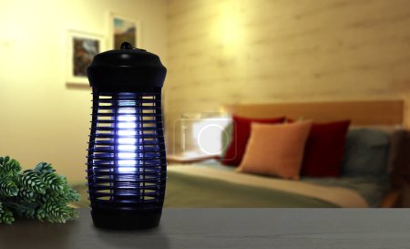 eine elektrische Blaulicht-Killer-Lampe für Insekten wird auf den Holztisch im schönen Schlafzimmer gestellt, um die Mücke während der Schlafzeit von Familienmitgliedern zu schützen