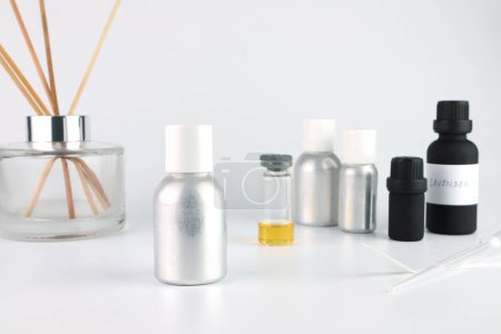 Photo for Aluminium essential oil bottle is on white table with blotting paper , chemical beaker , flask,and fragrance bottle are used to blend nice scent for making perfume and candle by perfumer in laboratory - Royalty Free Image