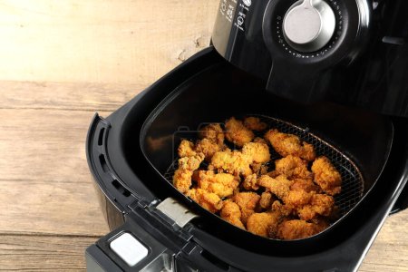 homemade deep fried chicken are cooked by using a black air fryer or oil free fryer on wooden table in the kitchen for being a dinner during the christmas party with family members