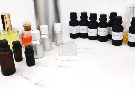 many types of essential oil bottles are on white table with blotting paper , fragrance bottle and digital scale are used to blend the nice scent for making perfume and candle by perfumer in laboratory