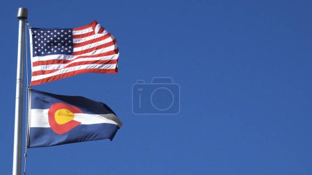 Téléchargez les photos : Drapeau américain et Colorado State Flag Long Shot présente une longue photo du drapeau américain au-dessus du drapeau de l'État du Colorado attaché à un mât de drapeau et soufflant dans le vent. - en image libre de droit