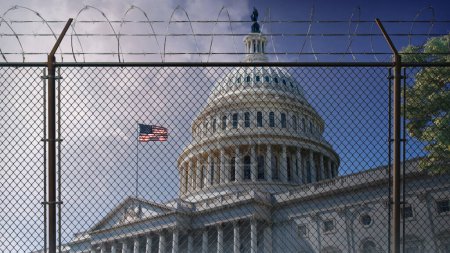 Photo for U.S. Capitol Building Behind Razor Wire Fence features a straight-on view of the U.S. Capitol Building with flag in the wind behind razor wire fence with clouds in the background. - Royalty Free Image