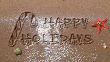 Foto de Felices Fiestas en la Playa presenta olas lavándose en una playa de arena y dejando atrás un mensaje de Felices Fiestas escrito en la arena, No I.A. generados. - Imagen libre de derechos