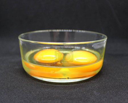 Téléchargez les photos : Les blancs et jaunes de deux œufs crus dans un bol en verre sont prêts pour faire une omelette - en image libre de droit