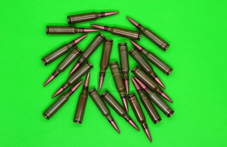 Foto de Live ammunitions with copper bullets scattered on a green top view - Imagen libre de derechos