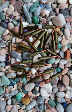 Téléchargez les photos : A bunch of live ammunition is thrown out of the magazine onto small pebbles - en image libre de droit