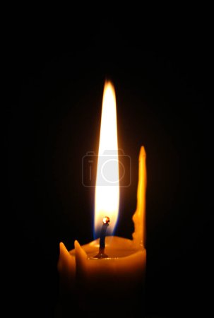 Photo for Single candle with wax streaks and an even flame in total darkness concept for backgrounds - Royalty Free Image