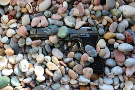 Photo for A gun sprinkled with small pebbles on a sea beach in the early morning - Royalty Free Image